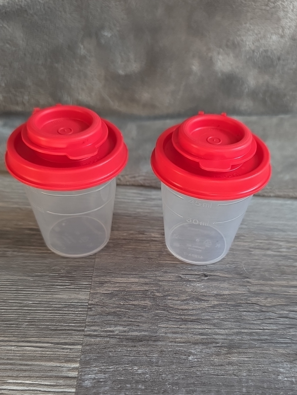 Tupperware Clear Salt And Pepper Shakers with Bright Red Lids.
